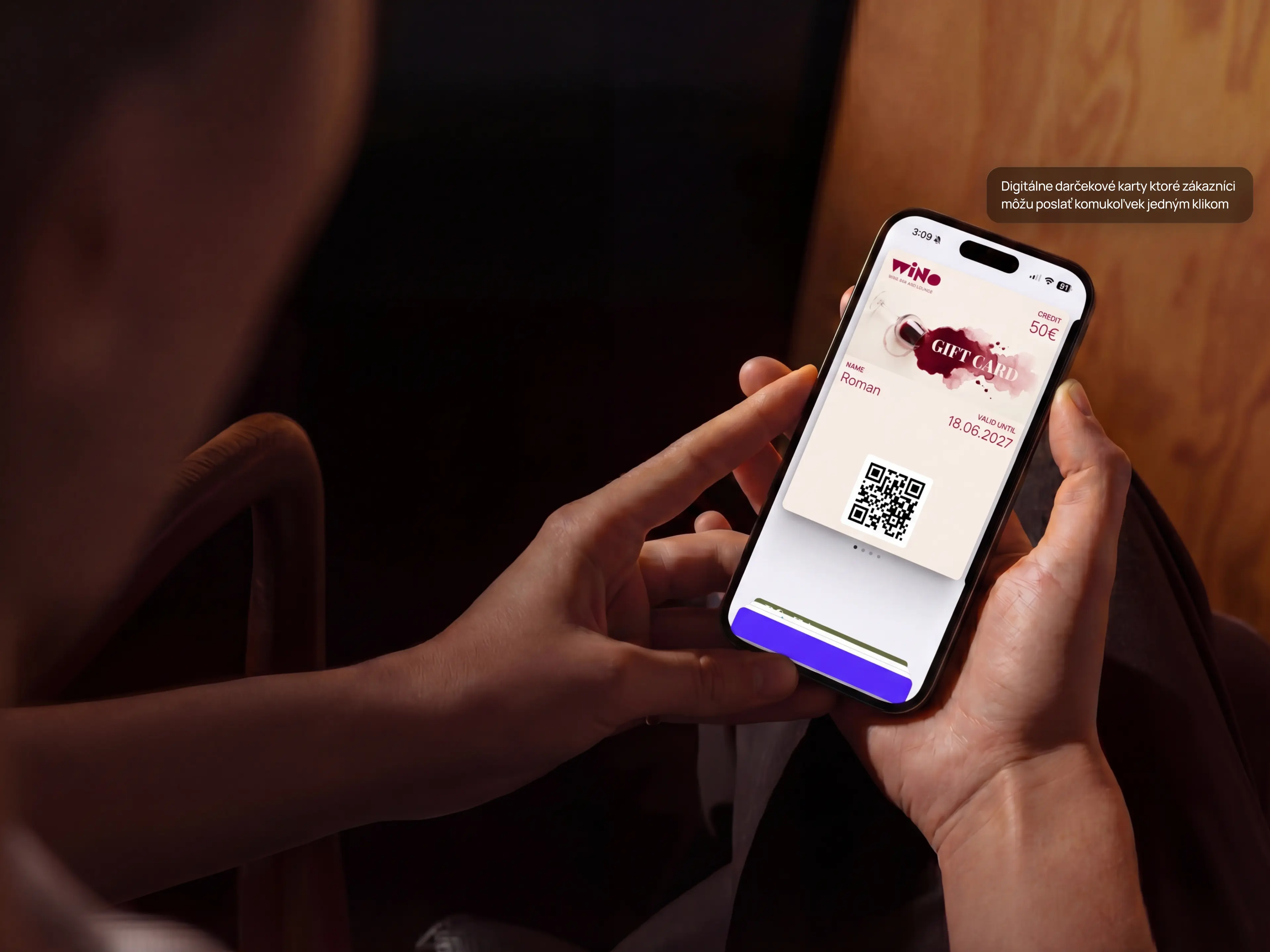 Ruky držia telefón s otvorenou značkovou darčekovou kartou vo Wallete, s kreditom a QR kódom